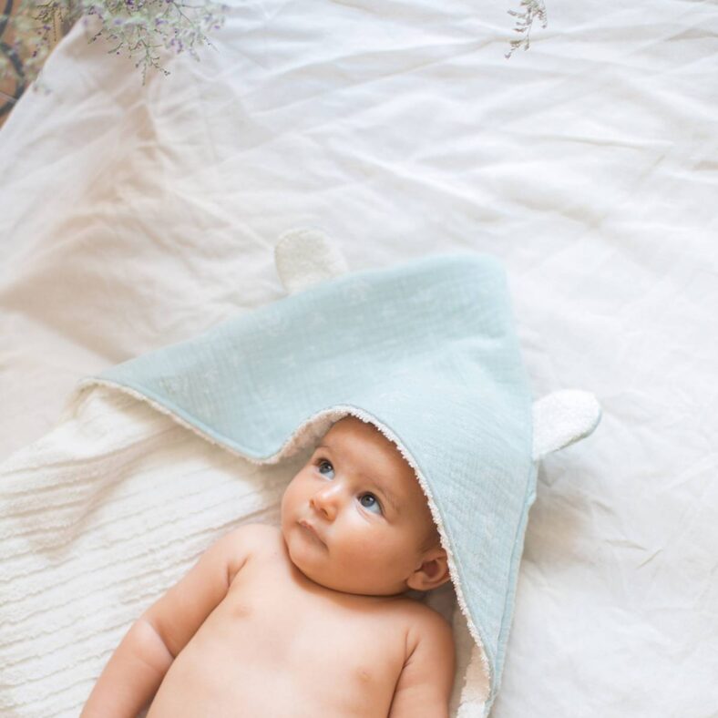 Bebé con capa de baño de rizo de algodón y muselina celeste
