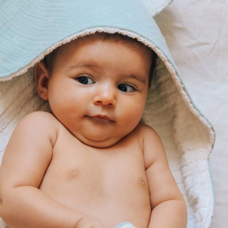 Bebé con capa de baño de rizo de algodón y muselina celeste