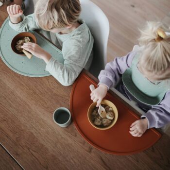 Niños comiendo con manteles individuales de silicona de Mushie